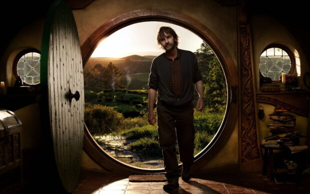 Peter Jackson is standing in a round doorway leading to a green landscape at sunset, 2K Desktop Wallpaper