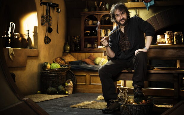 Peter Jackson wallpapers shows him holding a smoking pipe in a cozy wooden room, 2K Desktop Wallpaper