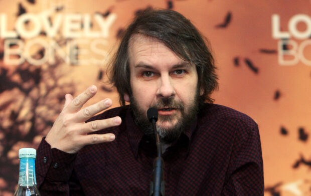 Peter Jackson is speaking at a press conference with an orange background and a microphone in front of him, 2K Desktop Wallpaper
