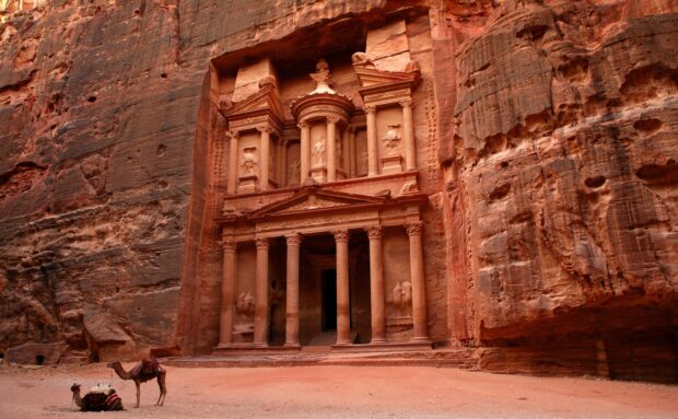 The ancient rock city of Petra Jordan features carved stone structures and camels in the foreground, 2K Desktop Wallpaper