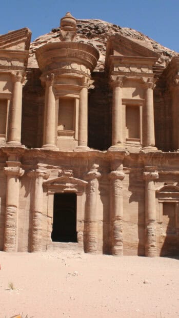 The Petra Jordan ancient stone monument stands in a desert landscape under a clear blue sky, 2K Mobile Wallpaper