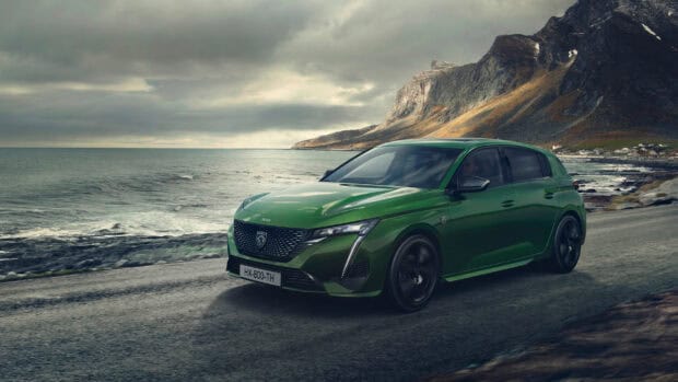 A green Peugeot 308 is driving along a coastal road with mountains in the background, 2K Desktop Wallpaper