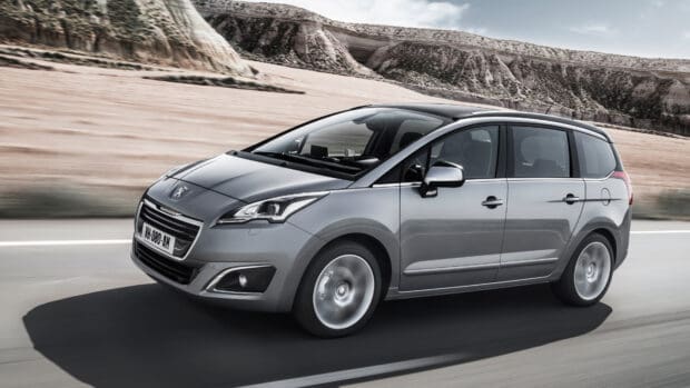 A silver Peugeot 5008 drives on a desert road with rocky hills in the background, 4K Desktop Wallpaper