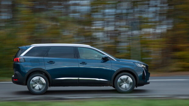 A blue Peugeot 5008 is driving on a road with blurred autumn trees in the background, 4K Desktop Wallpaper