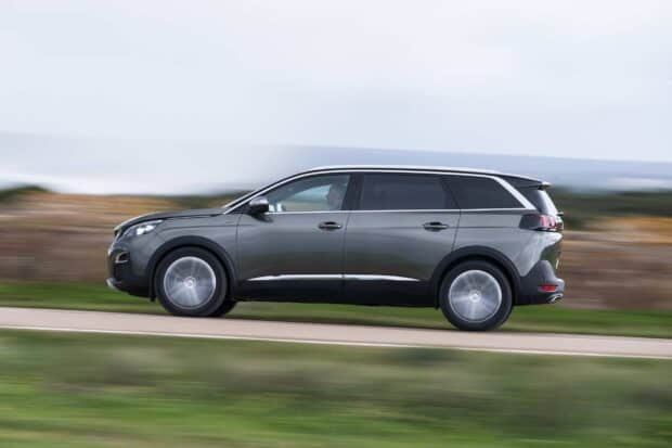 A Peugeot 5008 drives swiftly along a countryside road with blurred background showing its speed, HD Desktop Wallpaper