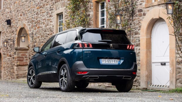 A Peugeot 5008 is parked near a rustic stone building with classic lanterns, 4K Desktop Wallpaper
