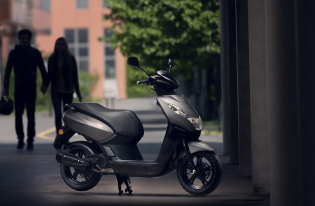 A Peugeot Kisbee is parked near a building with two people walking in the background, HD Desktop Wallpaper