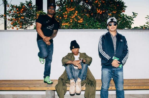 Pharrell Williams and two men posing near an orange tree on a bench, HD Desktop Wallpaper