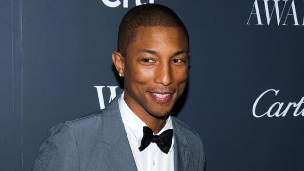 Pharrell Williams is smiling in a gray suit at an event, 2K Desktop Wallpaper