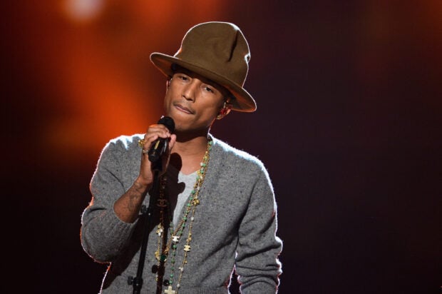 Pharrell Williams is singing into a microphone wearing a brown hat and layered necklaces, 2K Desktop Wallpaper