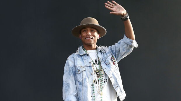 Pharrell Williams waving and smiling while wearing a hat and denim jacket, HD Desktop Wallpaper