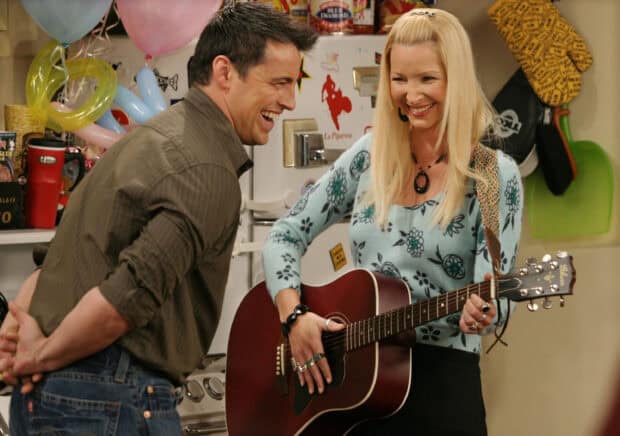 Phoebe Buffay is playing guitar while smiling in a room with a laughing man, 2K Desktop Wallpaper