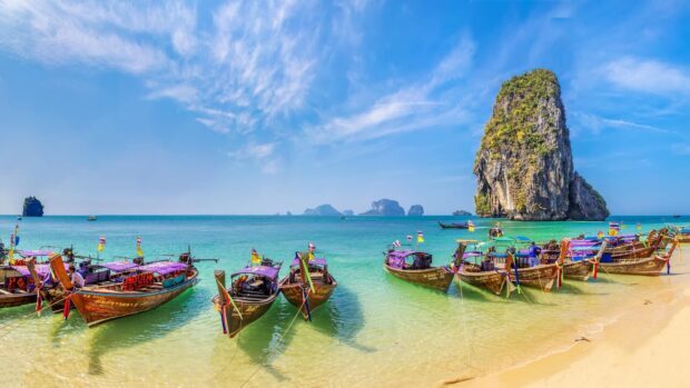 Traditional long tail boats lined up on a sandy beach in Phuket with turquoise water, 4K Desktop Wallpaper