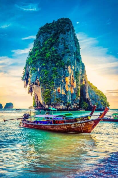 A traditional longtail boat floats near a large limestone island in the sea of Phuket, Phuket Wallpapers, 2K Phone Wallpaper