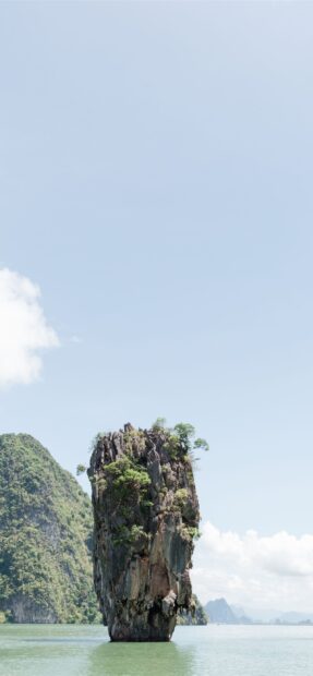 A tall limestone karst rock formation rises from the calm sea in Phuket scenery, 2K Phone Wallpaper