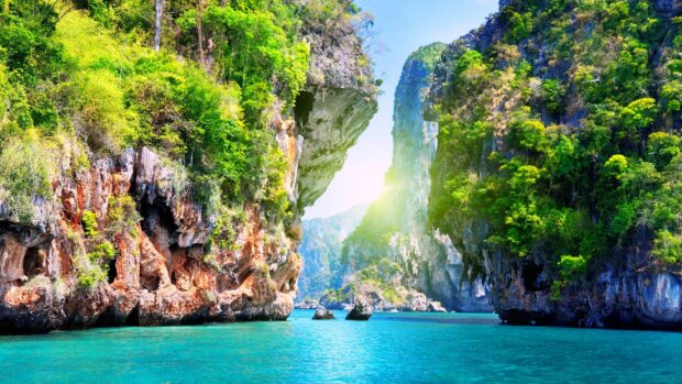 A stunning view of Phuket with clear turquoise water and forested limestone cliffs under a bright blue sky, 4K Desktop Wallpaper