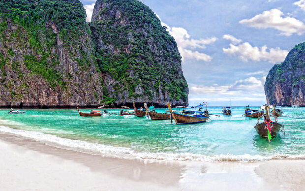 A vibrant view of Phuket with boats on turquoise water beside lush cliffs, 2K Desktop Wallpaper