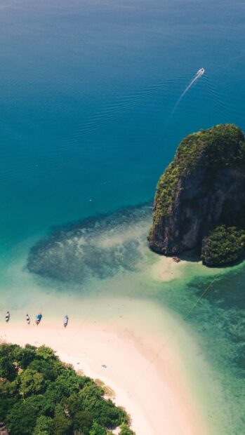 A boat sails near a lush island with clear blue water in Phuket Wallpapers HD and 4K, HD Mobile Wallpaper
