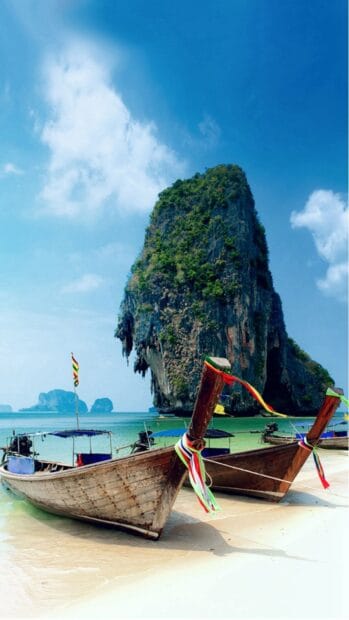 Two traditional boats rest on the shore near a large island in Phuket, HD Mobile Wallpaper