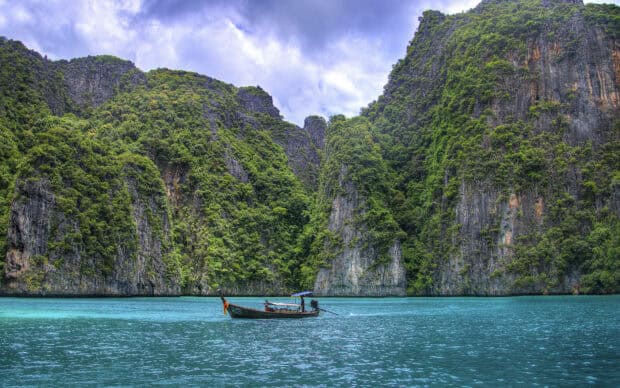 A traditional boat floats on clear blue water near lush cliffs in Phuket Wallpapers, HD Desktop Wallpaper