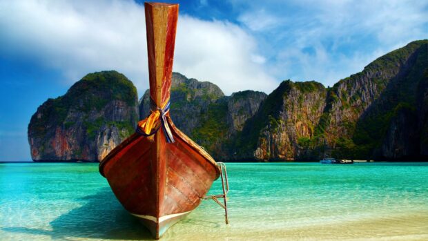 A traditional wooden boat rests on clear turquoise waters near limestone cliffs in Phuket, Phuket Wallpapers HD and 4K, HD Desktop Wallpaper