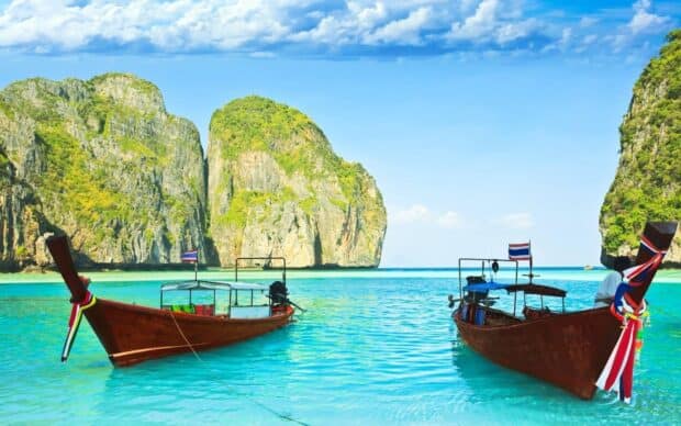 Two long tail boats float on clear turquoise water near rocky cliffs in Phuket, HD Desktop Wallpaper