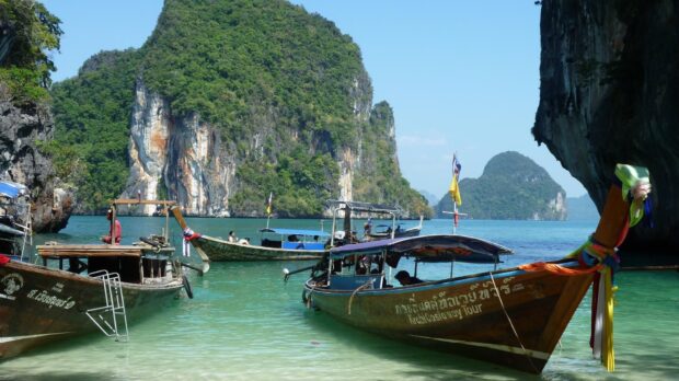 Traditional longtail boats float near green cliffs in Phuket, HD Desktop Wallpaper