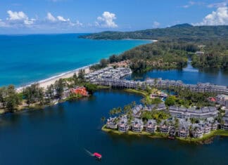 A scenic coastal view in Phuket showcases the turquoise sea and lush greenery with buildings, HD Desktop Wallpaper