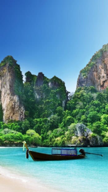 A traditional boat floats near the green cliffs under the clear blue sky in Phuket, HD Mobile Wallpaper