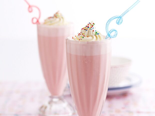 A pink milkshake topped with whipped cream and colorful sprinkles in a tall glass, HD Desktop Wallpaper