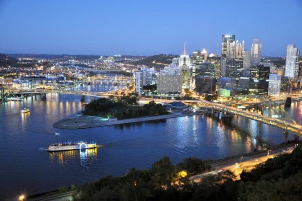 The Pittsburgh skyline features illuminated buildings and bridges reflecting on the river at twilight, 2K Desktop Wallpaper