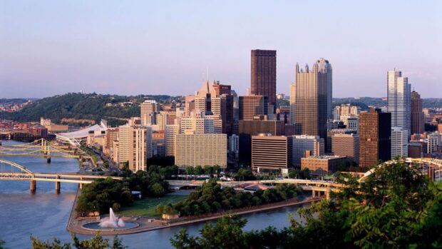 The Pittsburgh skyline shows tall buildings and river views in warm light, HD Desktop Wallpaper