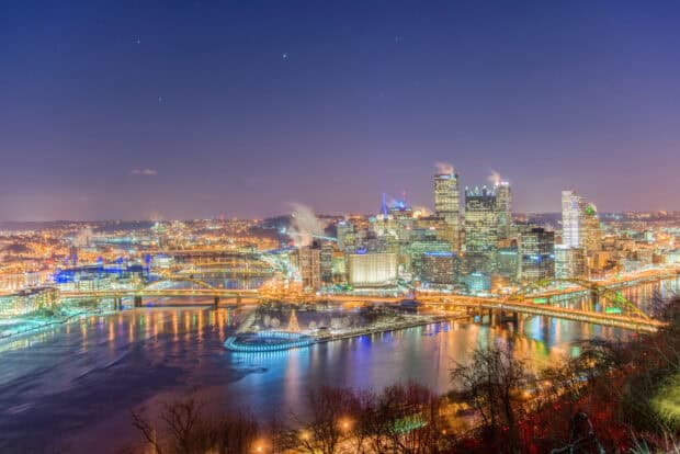 The Pittsburgh skyline displays bright lights reflecting on the calm river at night, HD Desktop Wallpaper