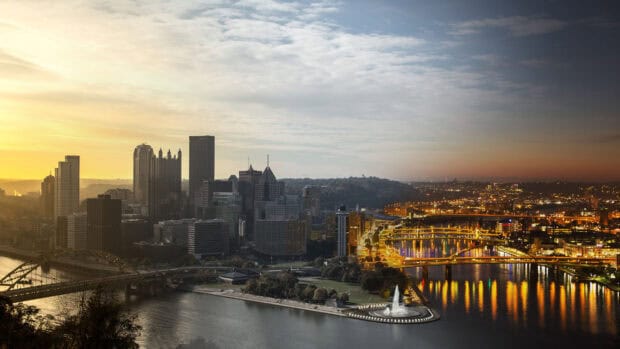 The Pittsburgh skyline at sunset reflects over the rivers with bright city lights and bridges, 2K Desktop Wallpaper