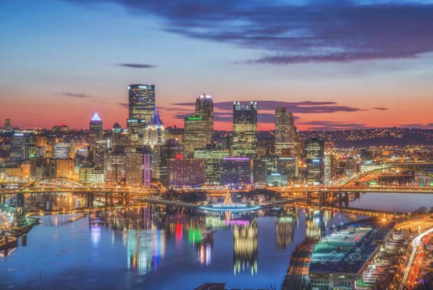 The Pittsburgh skyline at sunset is reflected in the river with illuminated buildings, HD Desktop Wallpaper