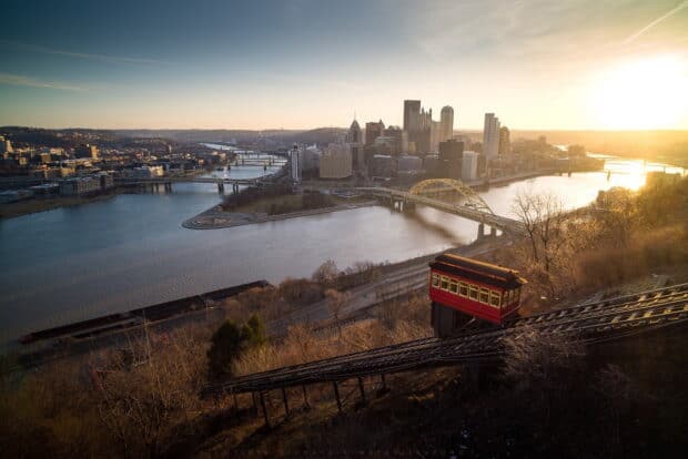 The Pittsburgh skyline is seen from a hill with a red incline car and rivers at sunset, HD Desktop Wallpaper