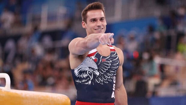 A male gymnast in a patriotic uniform points forward after a pommel horse routine, HD Desktop Wallpaper