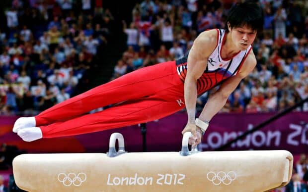 A gymnast is balancing on the pommel horse during a competition, HD Desktop Wallpaper