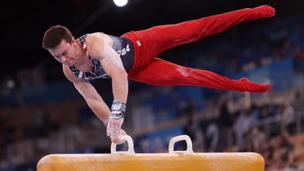 A gymnast is balancing on the pommel horse during a gymnastics competition, HD Desktop Wallpaper
