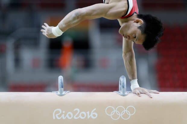 A gymnast performs on the pommel horse during a competition, HD Desktop Wallpaper