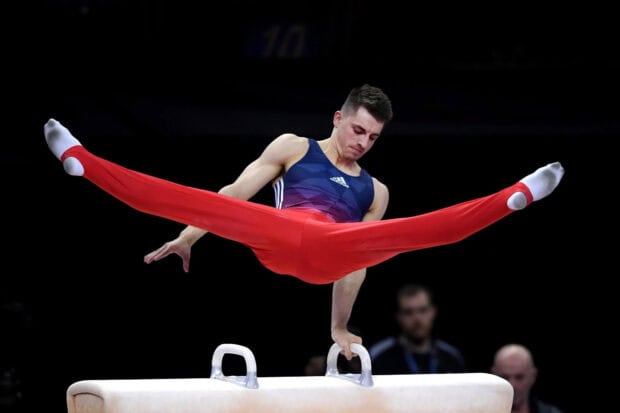 A male gymnast performs a pommel horse routine with legs spread wide, HD Desktop Wallpaper