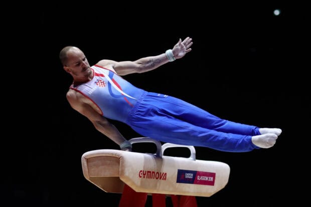 A gymnast performs a strength hold on the pommel horse during competition, HD Desktop Wallpaper