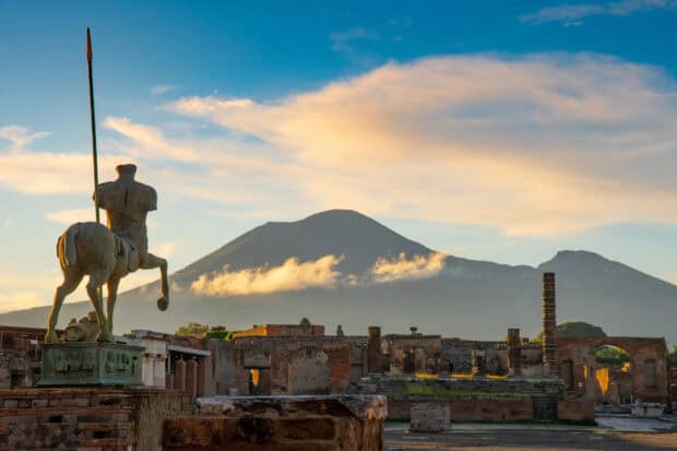 The Pompeii Wallpapers show ancient ruins with Mount Vesuvius rising in the background under a cloudy sky, HD Desktop Wallpaper