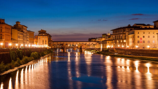 The Ponte Vecchio shows its historic charm reflected in the river at sunset, 4K Desktop Wallpaper