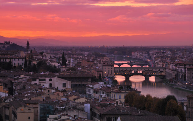 The Ponte Vecchio spans the river under a vibrant sunset sky in this Ponte Vecchio Wallpapers scene, 2K Desktop Wallpaper