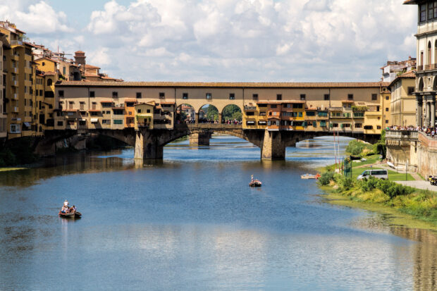 A scenic view of Ponte Vecchio with people on boats and old buildings along the river, 2K Desktop Wallpaper