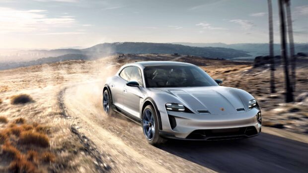 A silver Porsche Taycan is driving fast on a dusty dirt road in a mountainous area, 4K Desktop Wallpaper