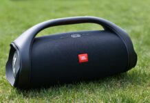 A portable JBL speaker is shown resting on green grass outdoors, 2K Desktop Wallpaper
