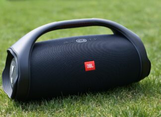 A portable JBL speaker is shown resting on green grass outdoors, 2K Desktop Wallpaper