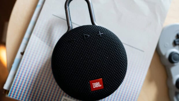 A black JBL speaker with volume and play buttons sitting on a magazine page, HD Desktop Wallpaper